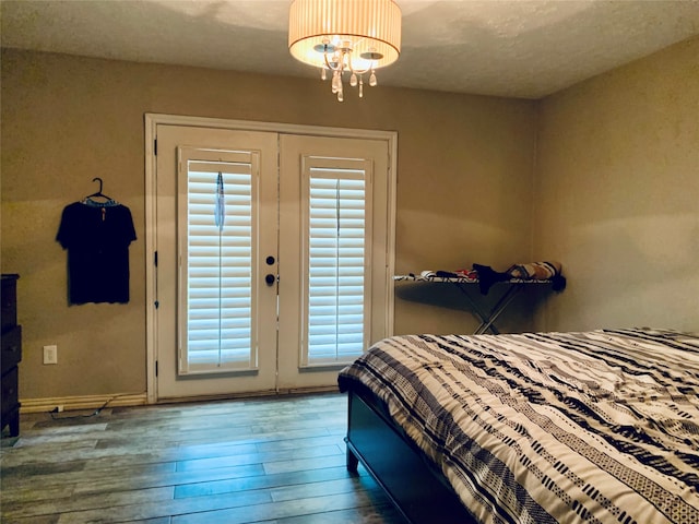 bedroom with french doors, a textured ceiling, an inviting chandelier, and wood-type flooring