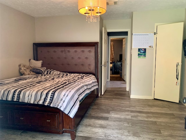 bedroom with a chandelier, hardwood / wood-style flooring, and a textured ceiling