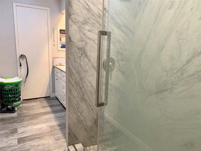 bathroom with a shower with door, hardwood / wood-style floors, and vanity