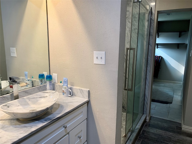 bathroom featuring a shower with shower door, oversized vanity, and hardwood / wood-style flooring