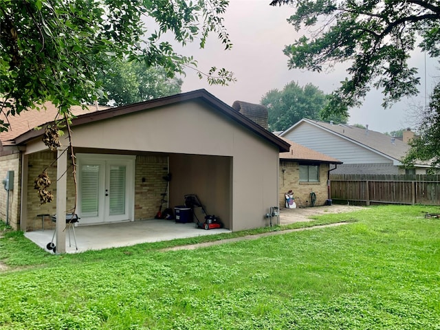 rear view of property featuring a yard, french doors, and a patio