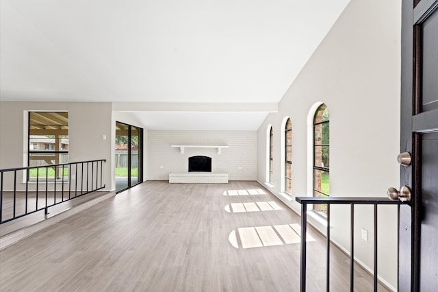 unfurnished living room featuring wood-type flooring and a brick fireplace