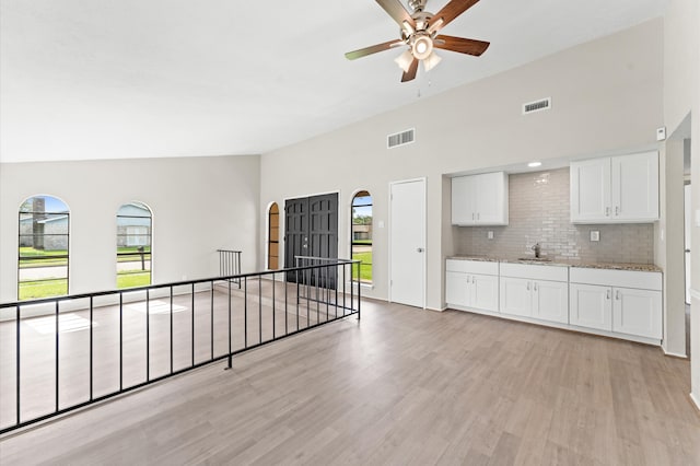 interior space featuring ceiling fan, light hardwood / wood-style floors, white cabinets, and backsplash