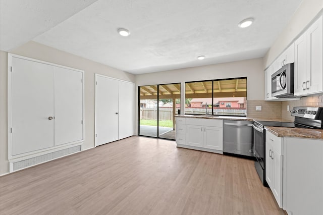 kitchen with backsplash, appliances with stainless steel finishes, white cabinetry, and light wood-type flooring