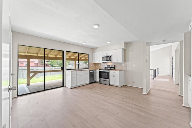 kitchen featuring light hardwood / wood-style floors, tasteful backsplash, white cabinets, sink, and appliances with stainless steel finishes