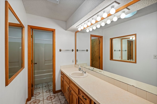 bathroom with a textured ceiling, tile flooring, and vanity with extensive cabinet space