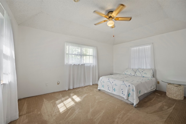 bedroom with lofted ceiling, a textured ceiling, carpet flooring, and ceiling fan