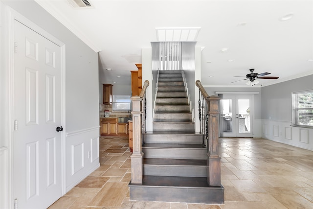 stairs with light tile floors, ornamental molding, ceiling fan, and french doors