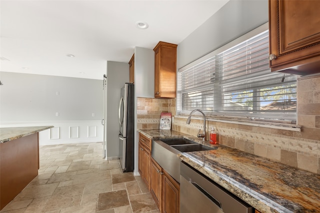 kitchen featuring dark stone countertops, appliances with stainless steel finishes, sink, tasteful backsplash, and light tile flooring