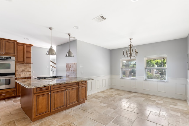 kitchen featuring appliances with stainless steel finishes, light tile flooring, backsplash, hanging light fixtures, and a chandelier