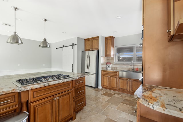 kitchen with stainless steel appliances, decorative light fixtures, a barn door, sink, and light tile flooring