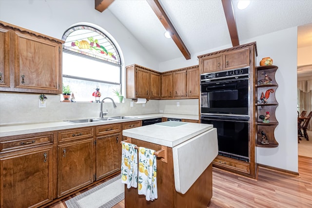 kitchen featuring black appliances, sink, light hardwood / wood-style floors, and vaulted ceiling with beams