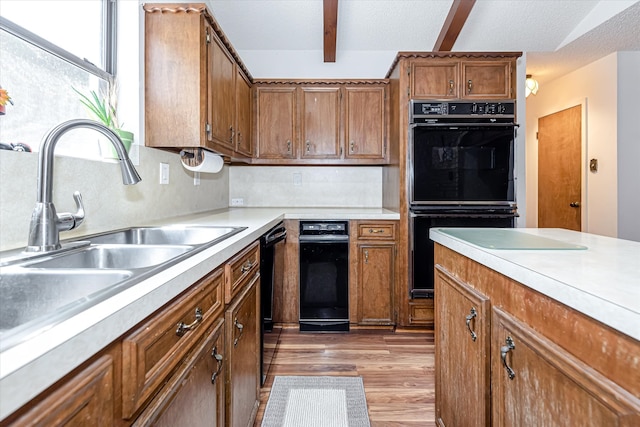 kitchen with sink, black appliances, light hardwood / wood-style floors, and tasteful backsplash