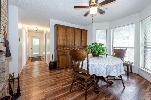 dining room with ceiling fan, a healthy amount of sunlight, a textured ceiling, and dark wood-type flooring