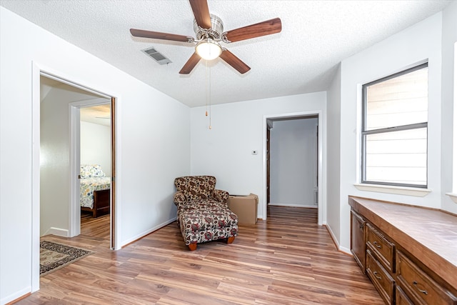 sitting room with a textured ceiling, ceiling fan, and hardwood / wood-style floors