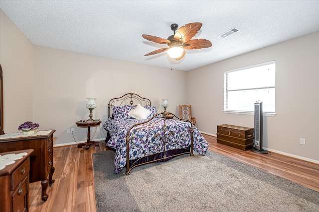 bedroom with wood-type flooring, ceiling fan, and a textured ceiling