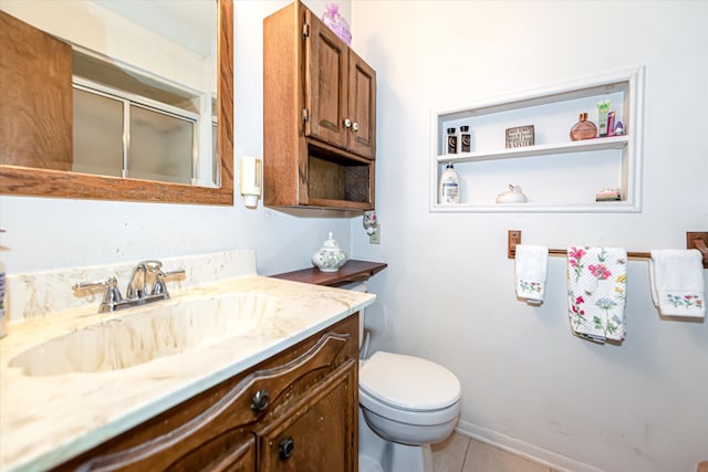 bathroom featuring tile flooring, vanity, and toilet