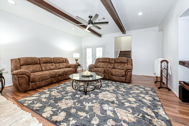 living room featuring french doors, a textured ceiling, beamed ceiling, hardwood / wood-style floors, and ceiling fan