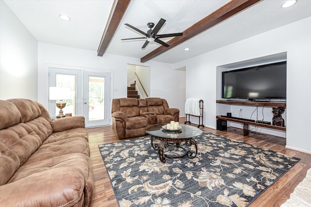 living room featuring wood-type flooring, ceiling fan, beamed ceiling, french doors, and a textured ceiling