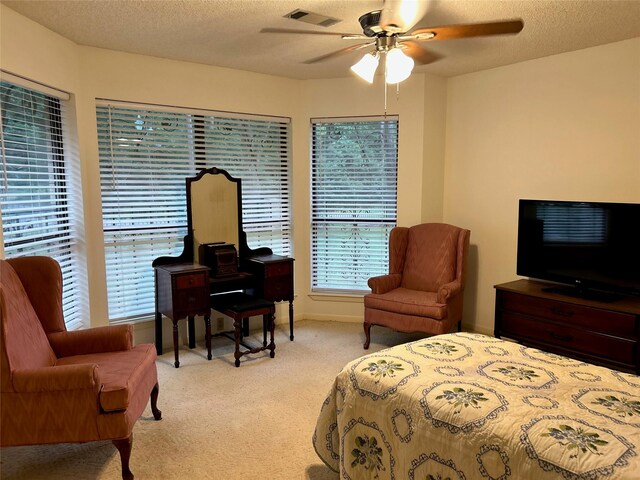 carpeted bedroom featuring ceiling fan and a textured ceiling