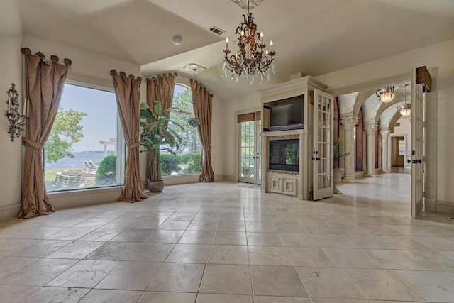 unfurnished living room with a notable chandelier, lofted ceiling, and light tile floors