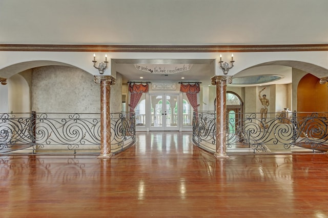 foyer with ornate columns, hardwood / wood-style floors, french doors, and crown molding