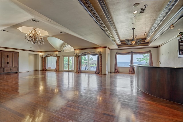 unfurnished living room featuring a tray ceiling, a healthy amount of sunlight, and hardwood / wood-style floors