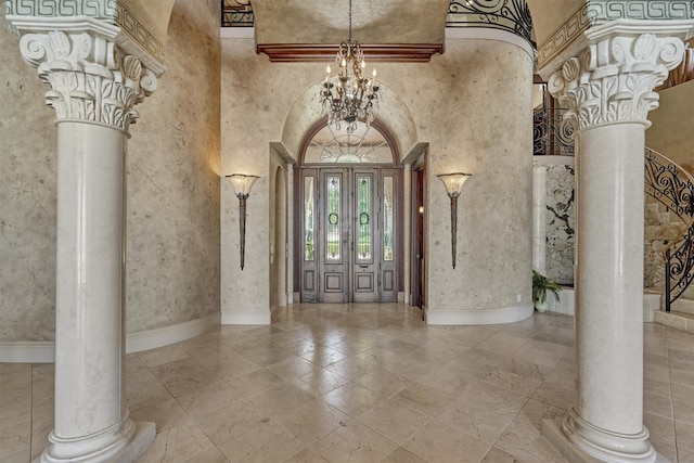 entryway featuring ornate columns, an inviting chandelier, a towering ceiling, and tile flooring