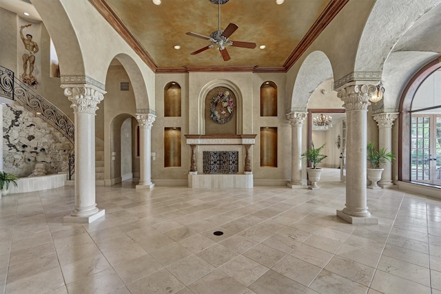 unfurnished living room with a high ceiling, ceiling fan, a fireplace, and ornate columns