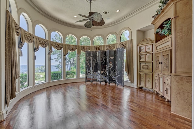 empty room with a wealth of natural light, ornamental molding, and wood-type flooring