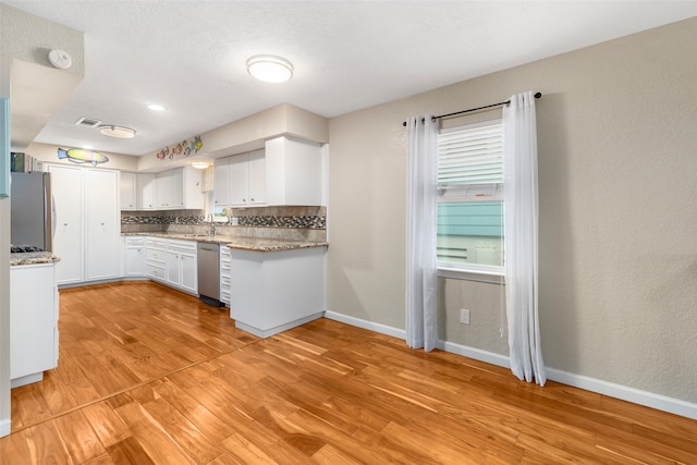 kitchen with light hardwood / wood-style floors, tasteful backsplash, sink, white cabinets, and appliances with stainless steel finishes