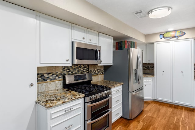 kitchen with light hardwood / wood-style floors, backsplash, white cabinetry, and stainless steel appliances