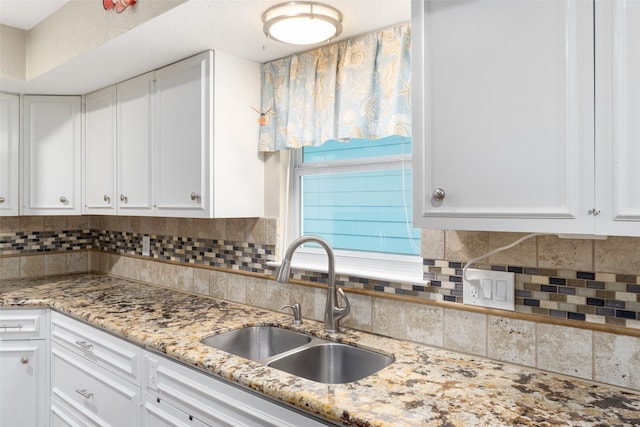 kitchen featuring sink, white cabinets, tasteful backsplash, and light stone counters