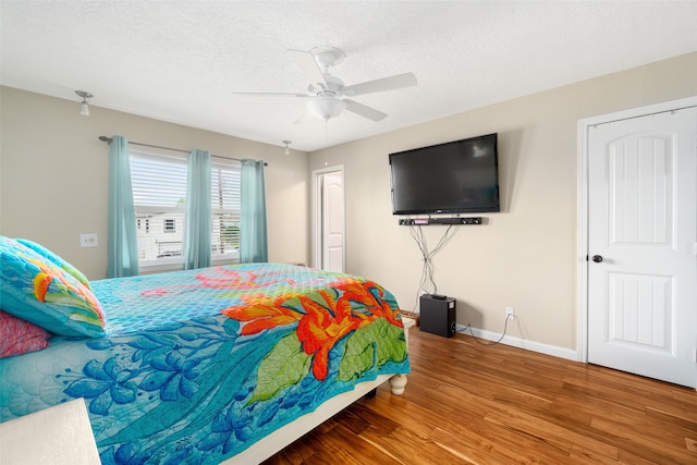 bedroom with a textured ceiling, ceiling fan, and hardwood / wood-style floors