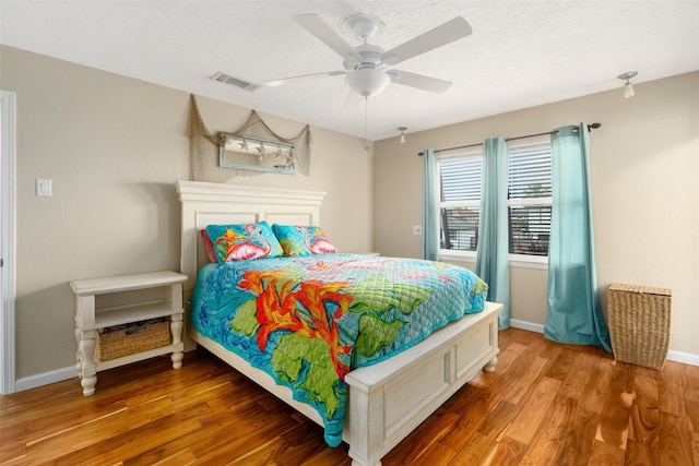 bedroom featuring a textured ceiling, ceiling fan, and hardwood / wood-style floors