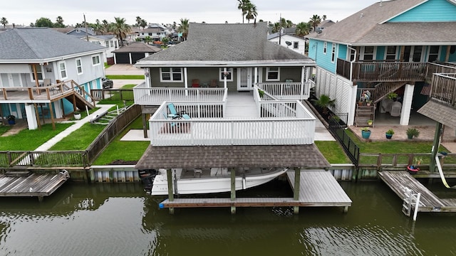 back of house with a deck with water view and a yard