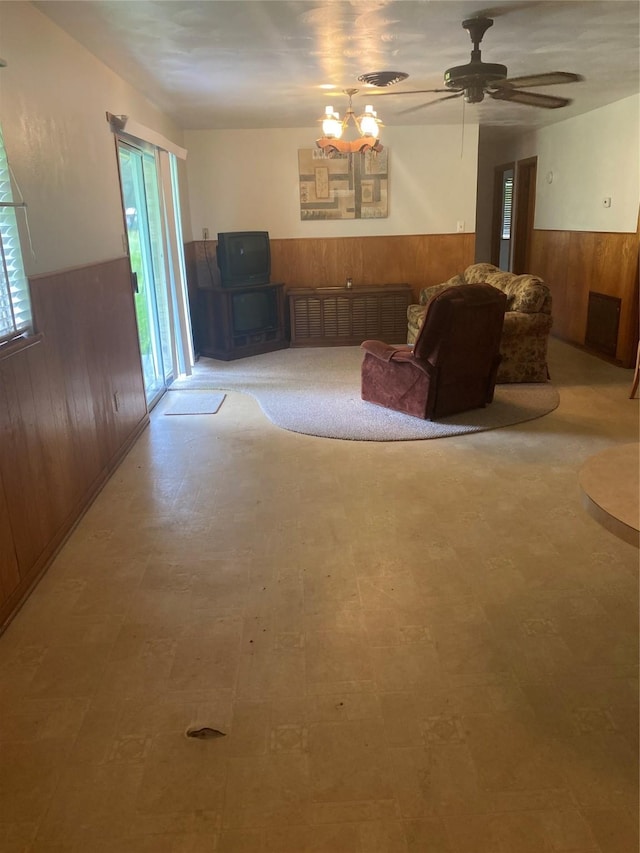 unfurnished room featuring ceiling fan with notable chandelier and wooden walls