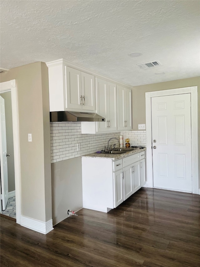 kitchen featuring white cabinets, a textured ceiling, tasteful backsplash, and dark hardwood / wood-style floors