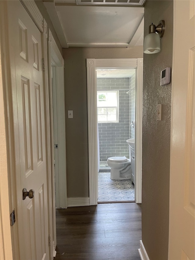 corridor with dark tile floors and tile walls