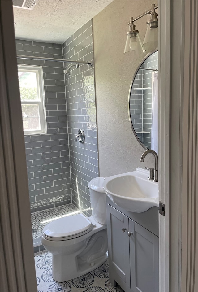 bathroom with toilet, tile floors, walk in shower, vanity, and a textured ceiling