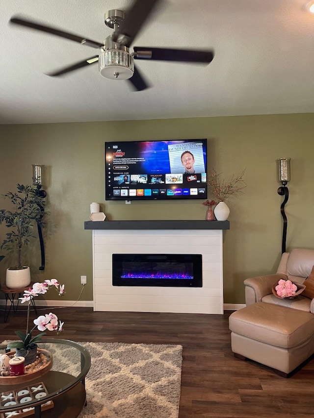 living room with a textured ceiling, ceiling fan, and dark wood-type flooring