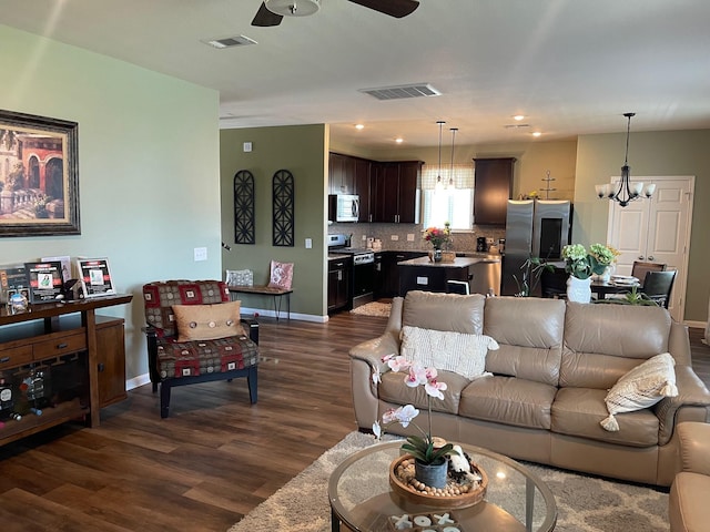 living room with ceiling fan with notable chandelier and dark hardwood / wood-style floors