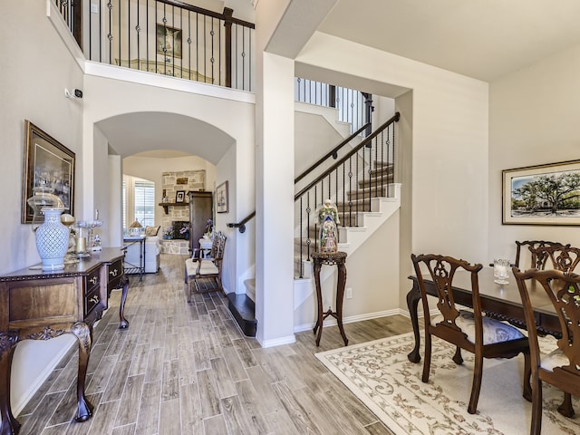 foyer entrance featuring hardwood / wood-style flooring, a stone fireplace, and a towering ceiling