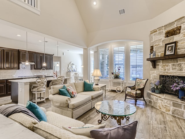 living room featuring light hardwood / wood-style floors, a fireplace, and high vaulted ceiling