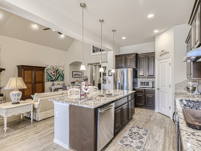 kitchen featuring stainless steel appliances, light hardwood / wood-style flooring, backsplash, pendant lighting, and a kitchen island with sink