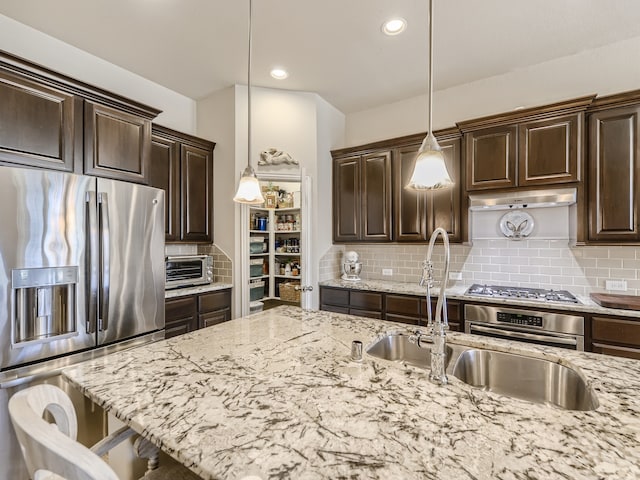 kitchen with decorative light fixtures, stainless steel appliances, a breakfast bar area, and tasteful backsplash