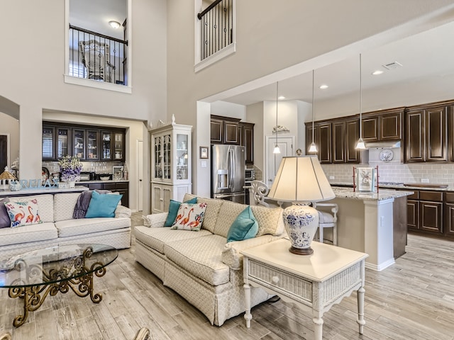 living room with light hardwood / wood-style floors and a towering ceiling