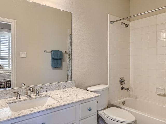 full bathroom with tiled shower / bath, vanity, and toilet