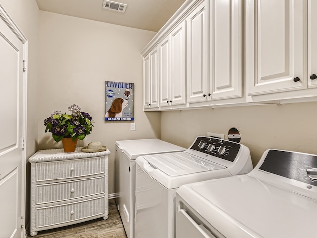 washroom featuring washing machine and dryer, cabinets, and hardwood / wood-style flooring