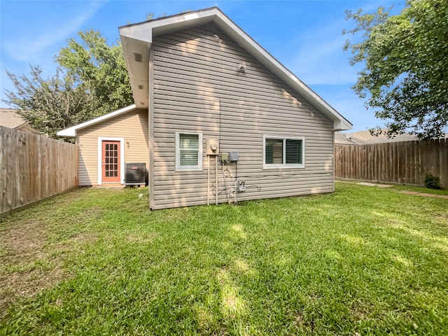 back of house with central AC and a lawn